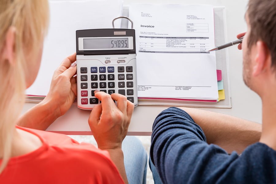 High Angle View Of Couple Calculating Invoice Taxes And Family Budget At Home High Angle View Of Couple Calculating Invoice Taxes And Family Budget At Home